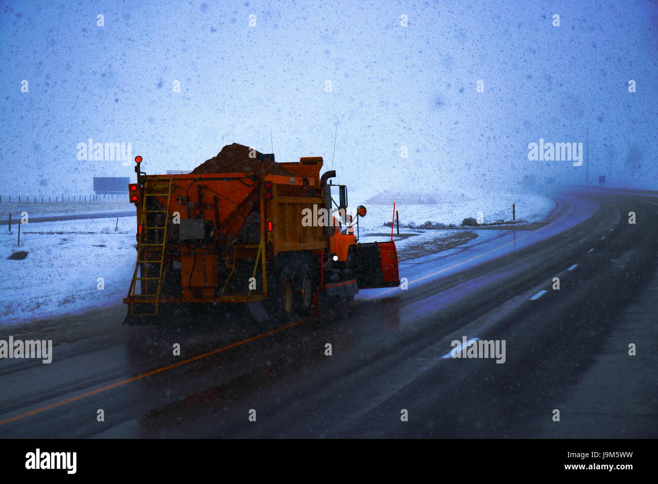 A yellow/orange snow plow parked in the median of Interstate in Wyoming