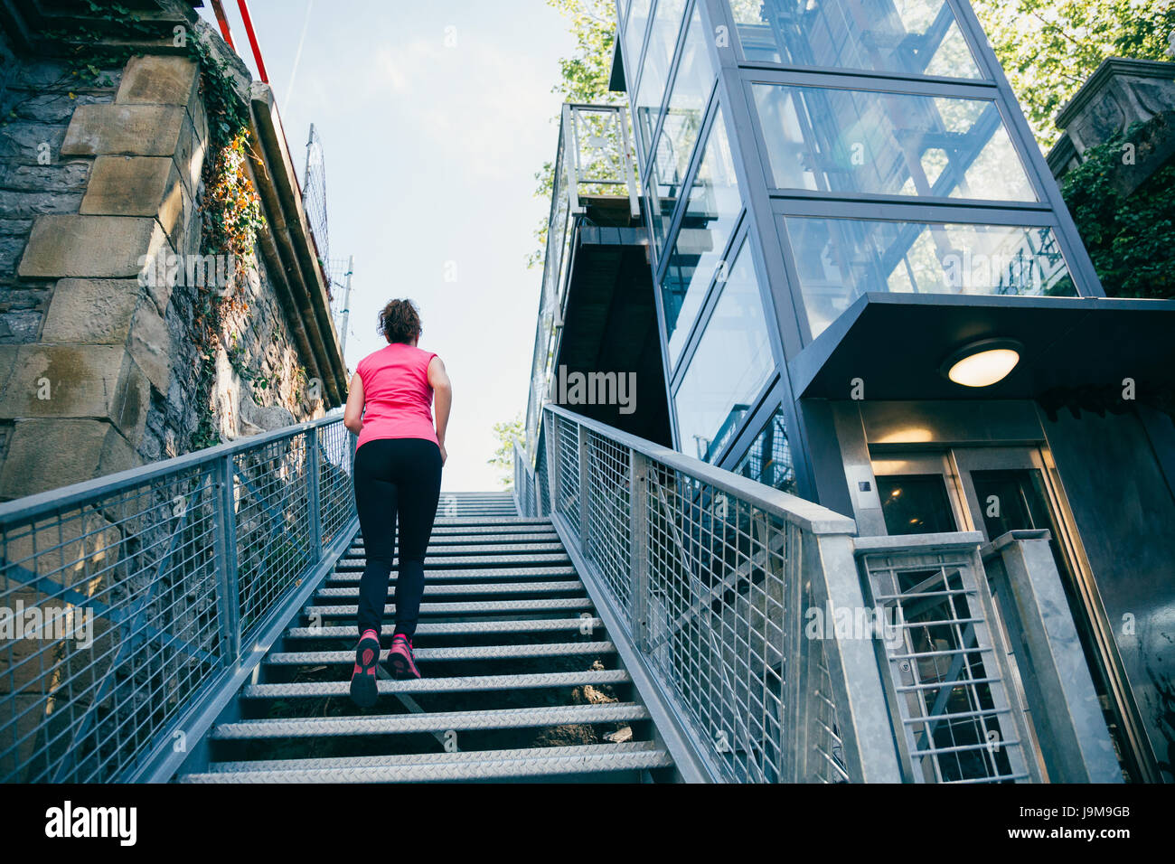 Middle aged woman climbing metallic stairs fast next to a elevator outdoors Stock Photo Alamy