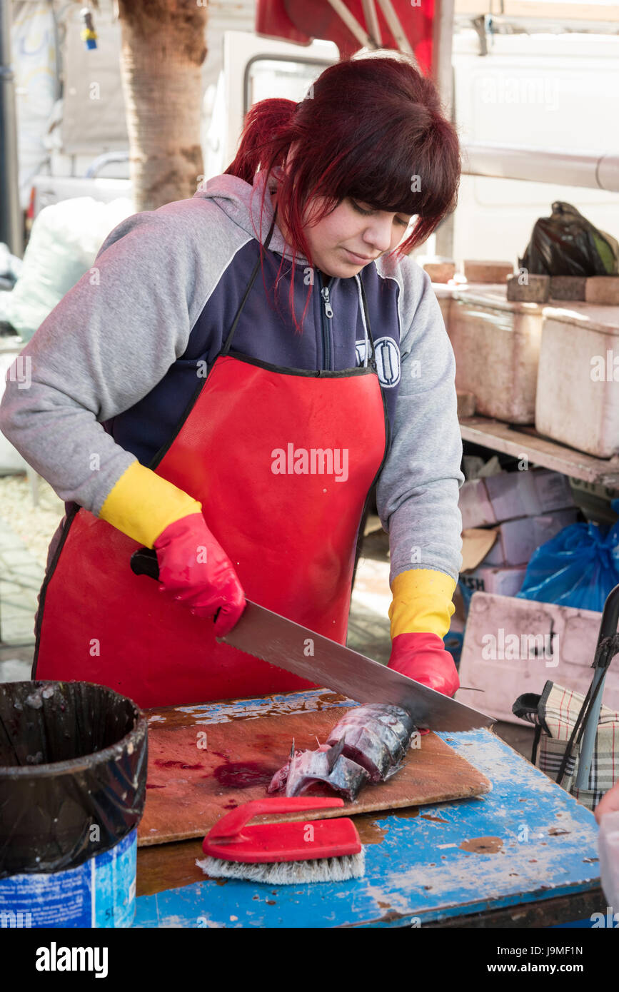 A fishmonger cutting up fish on a market stall in the market at Marsaxlokk Malta Stock Photo