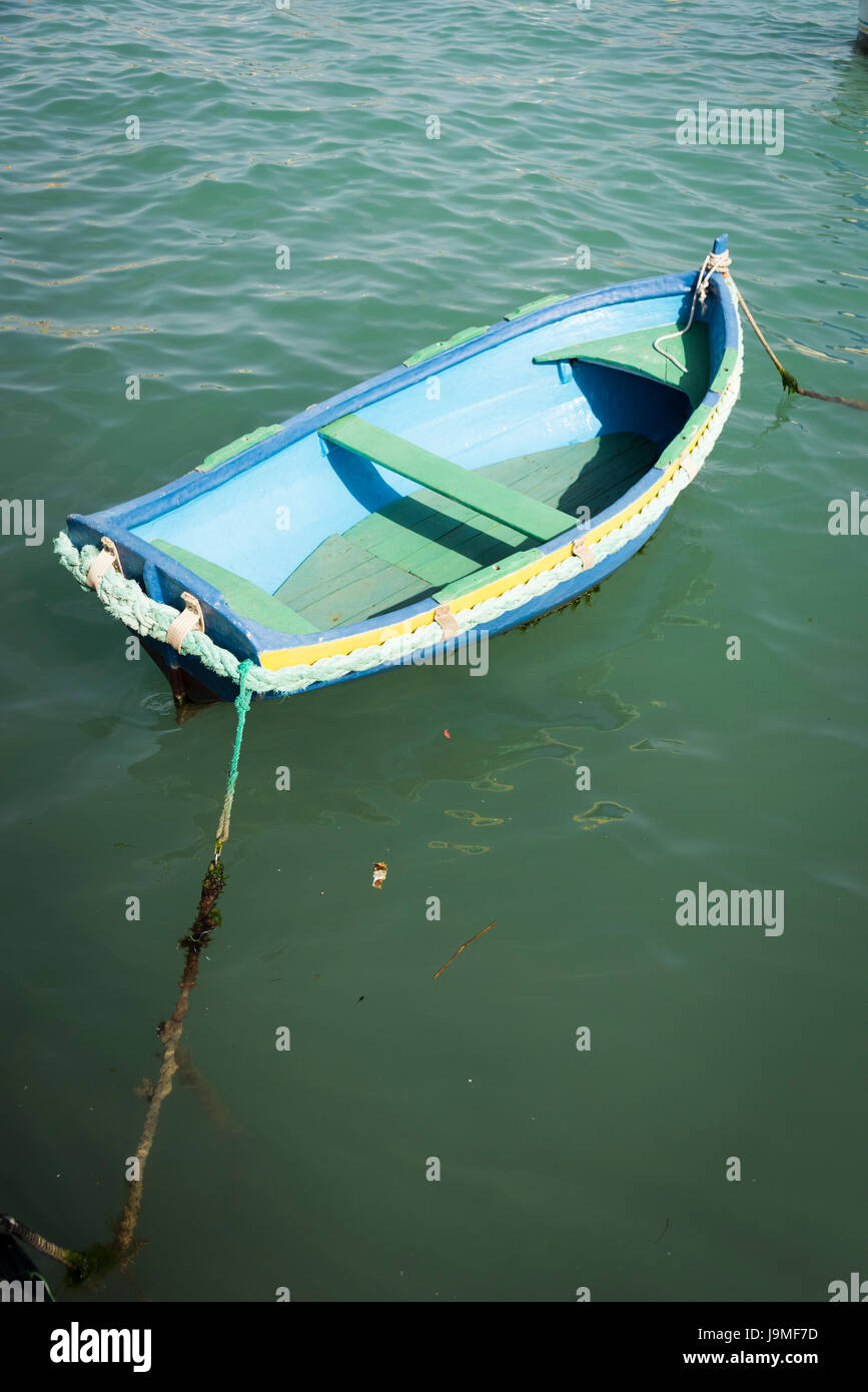 A brightly blue painted small wooden rowing boat in the harbour at Marsaxlokk Malta Stock Photo