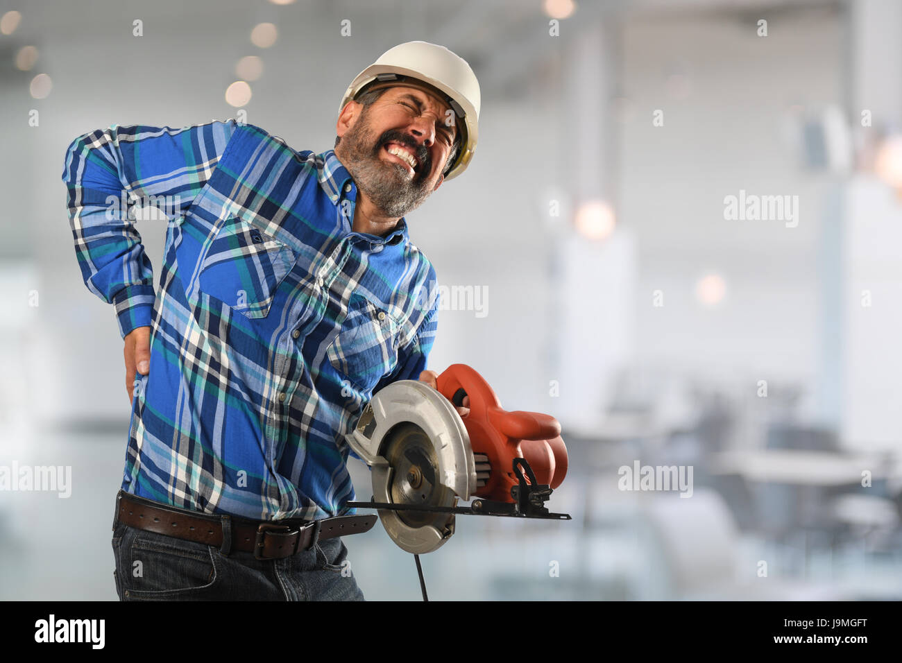 Senior Hispanic worker suffering  back injury inside building Stock Photo