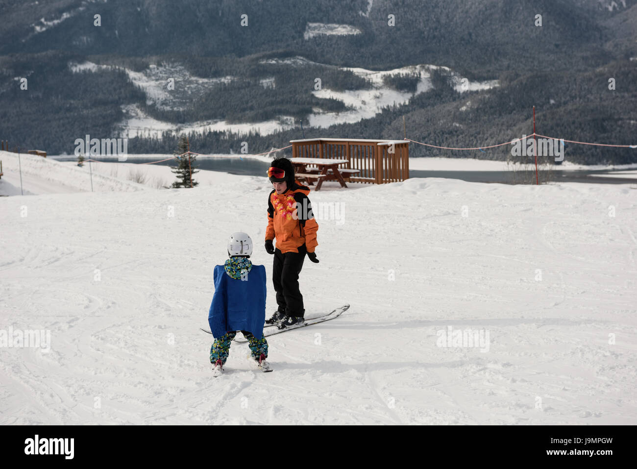 Little boy learning to ski with instructor on snowy slope in ski resort Stock Photo