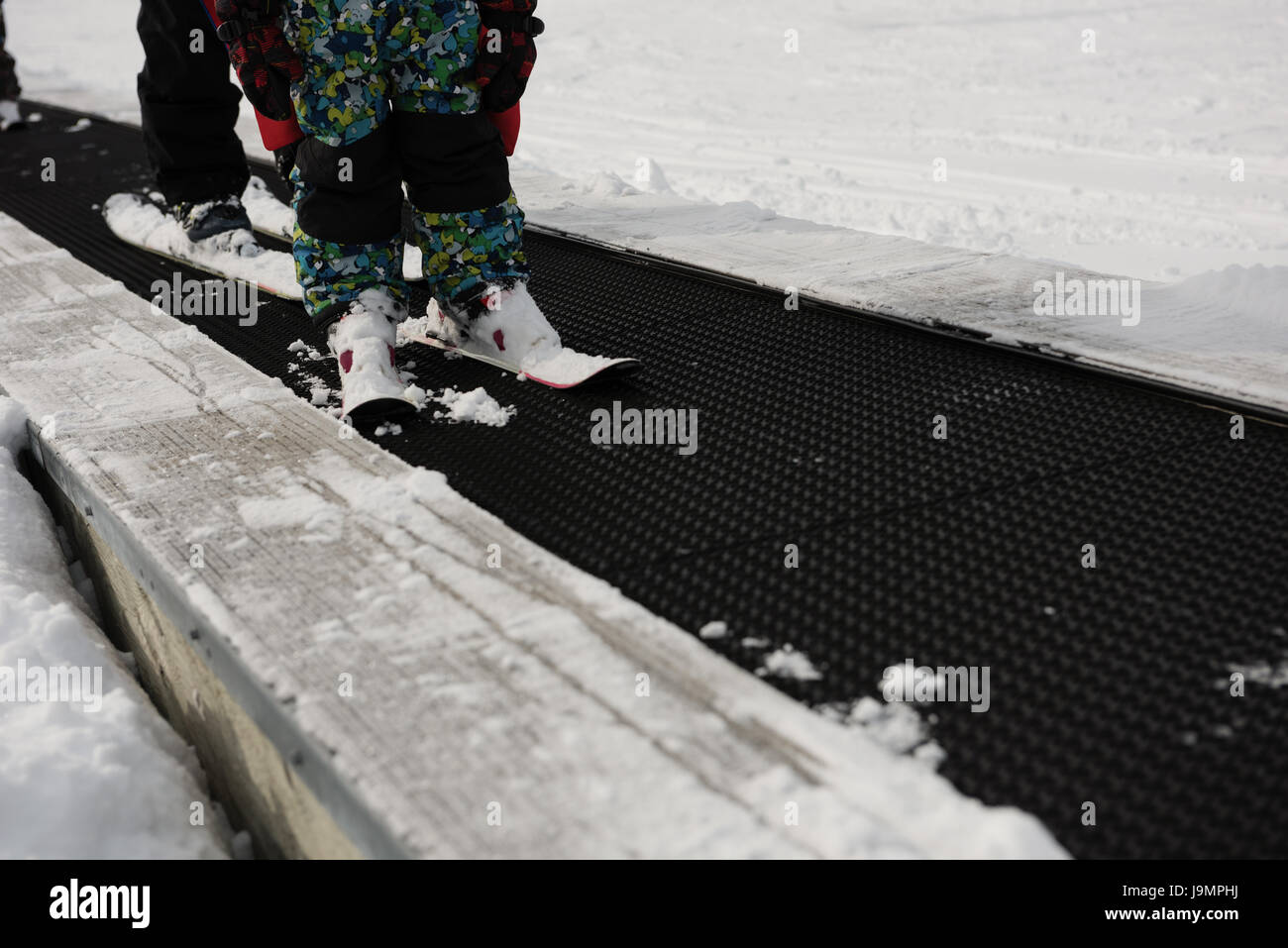 Low-section of little boy learning to ski with instructor in ski resort Stock Photo