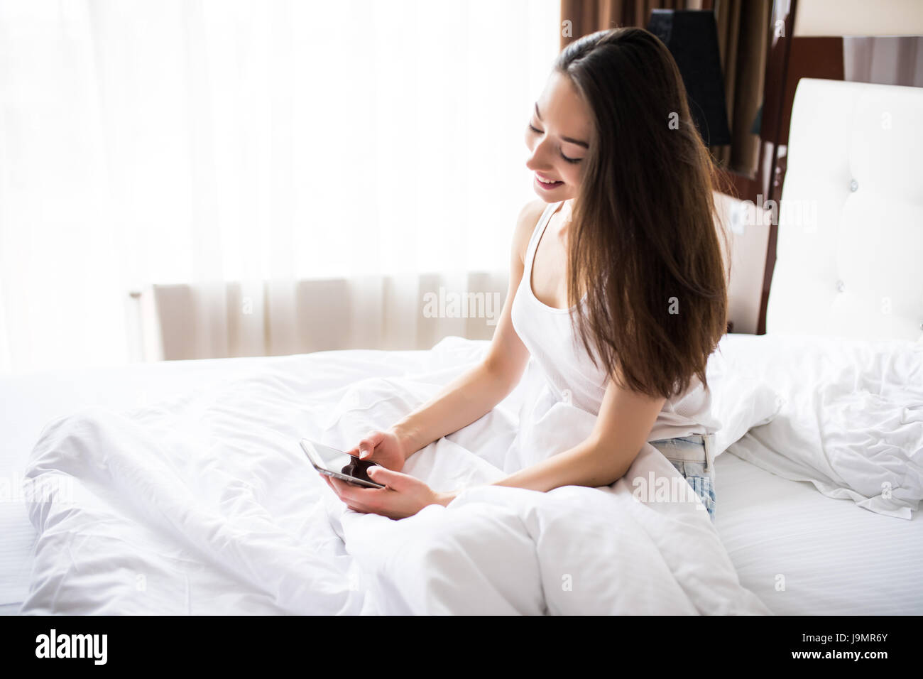 Woman Lying In Bed Reaching To Check Mobile Phone Stock Photo - Alamy