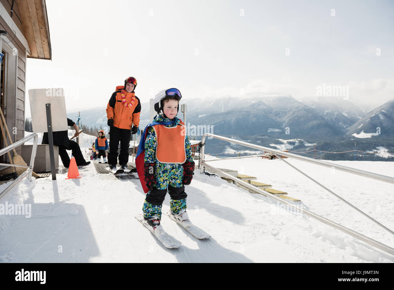 Little boy learning to ski with instructor on snowy slope in ski resort Stock Photo