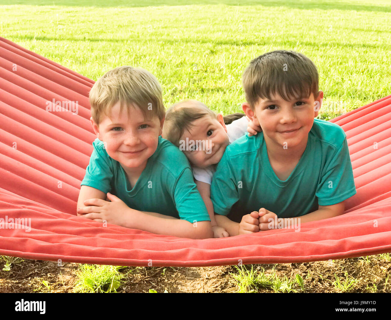 Three boys on red hammock Stock Photo