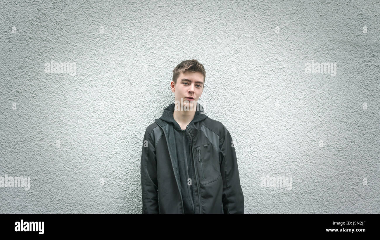 portrait of a young man leaning against a white wall Stock Photo - Alamy