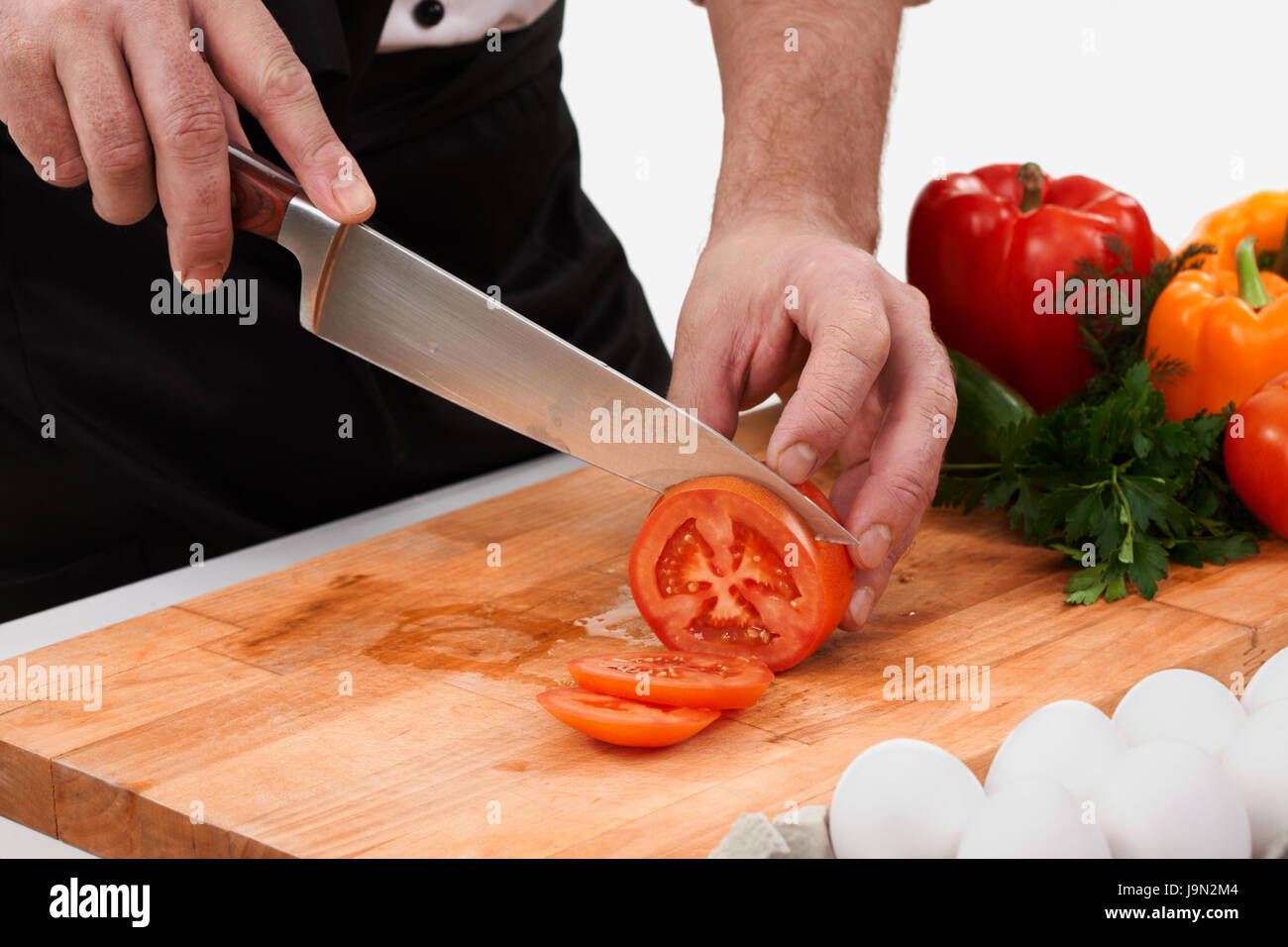 Нож режет овощи. Разрезка овощей на доске разделочной. Нож разрезает помидор. Нарезанные помидоры на деревянной доске. Режут на разделочной доске.