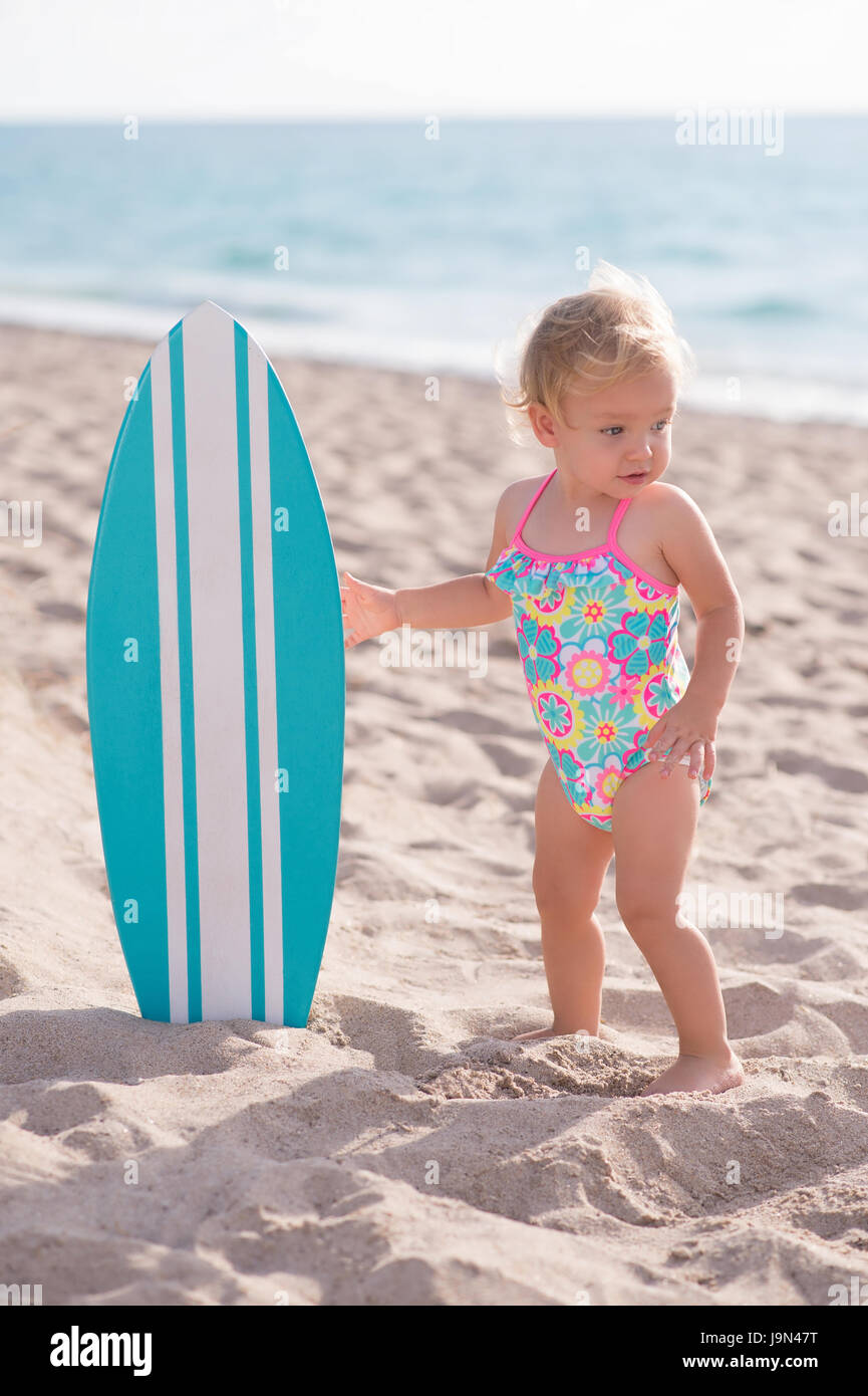 A One Year Old Baby Girl Holding An Aqua Blue Surfboard Shot Stock Photo Alamy