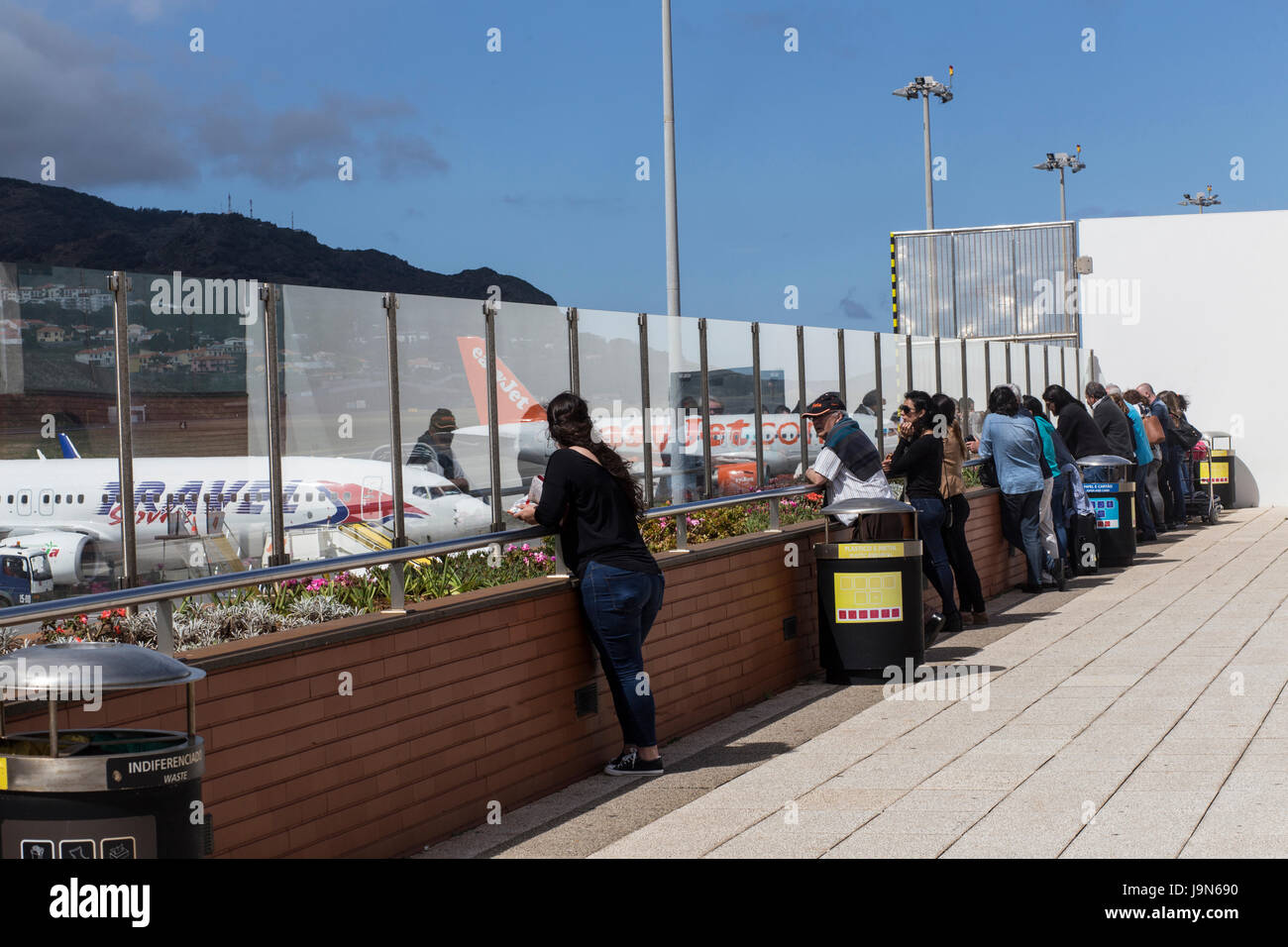 Passengers at Madeira Airport, near Fuchal, recently renamed Christiano Ronaldo International Airport looking at the runway and planes. Stock Photo