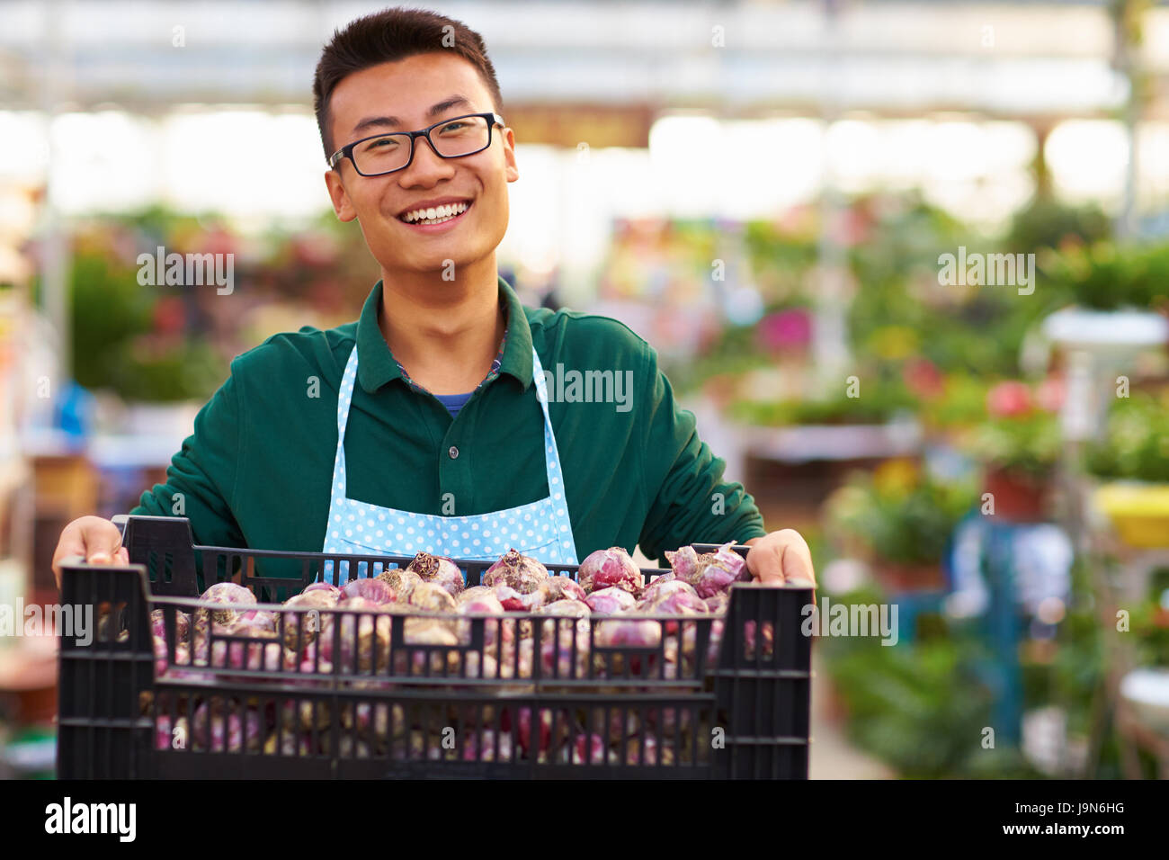 One Young Happy Asian Male Florist Working in Shop with many plant or flower around Stock Photo