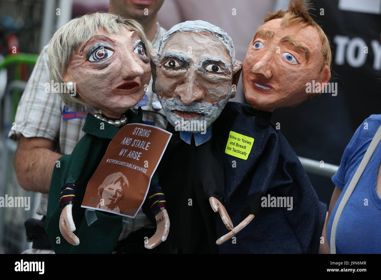 NOTE LANGUAGE ON SIGNS A demonstrator holds paper mache puppets of (left to right) Prime Minister Theresa May, Labour leader Jeremy Corbyn and Liberal Democrats leader Tim Farron outside the BBC Broadcasting House in London, where they are protesting over Radio 1's refusal to play the Liar Liar song. Stock Photo