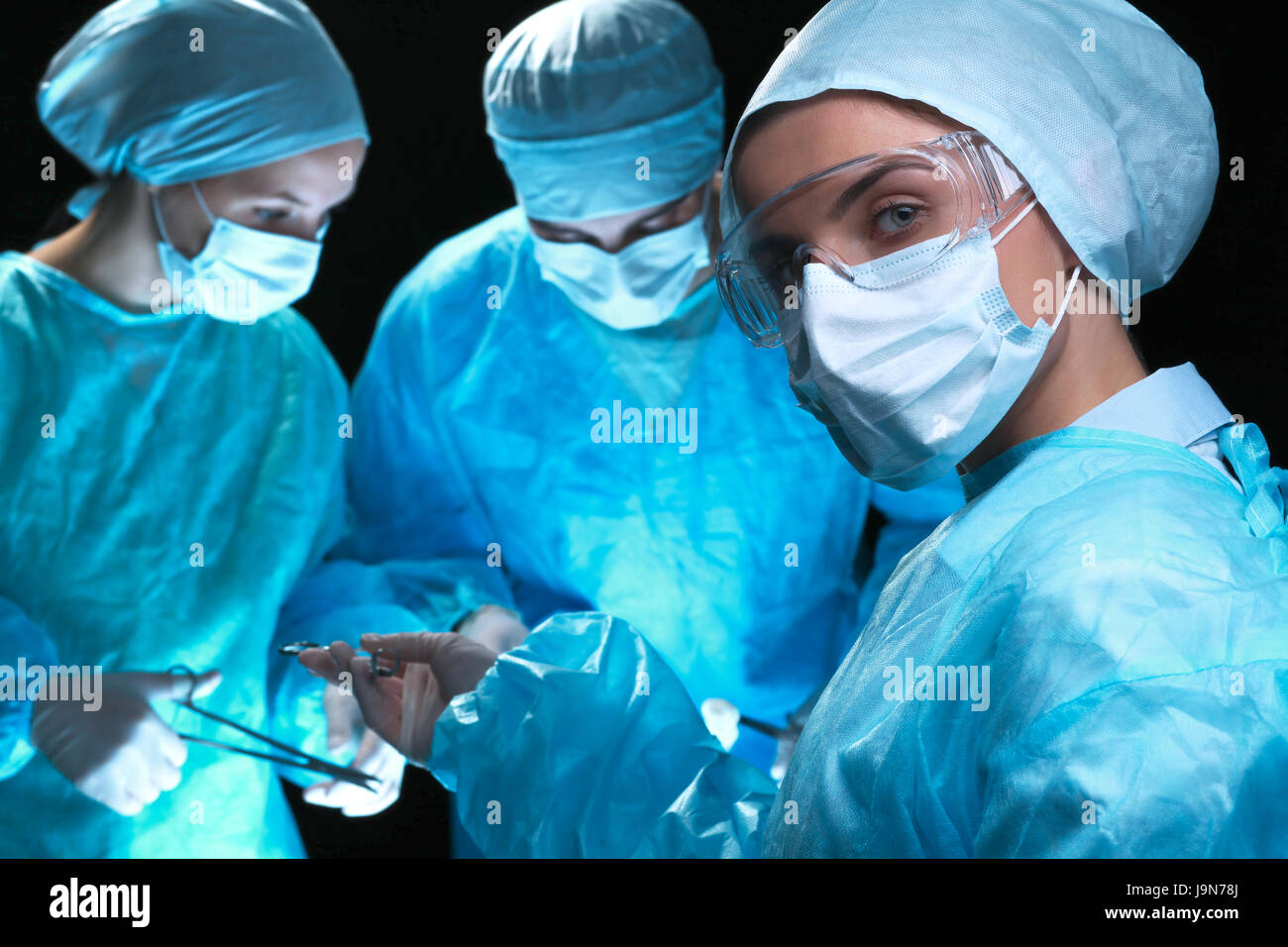 Three surgeons at work operating in surgical theater saving patient and ...