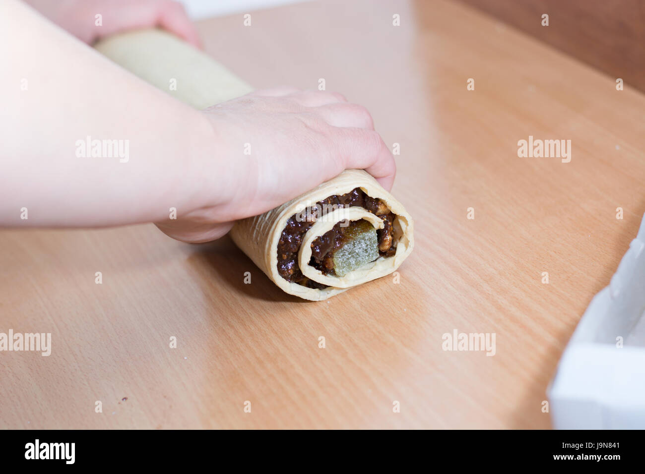 Rolling cake crust with chocolate and jelly candies. Preparing it for cutting with knife Stock Photo