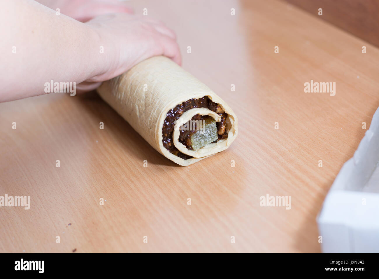 Rolling cake crust with chocolate and jelly candies. Preparing it for cutting with knife Stock Photo