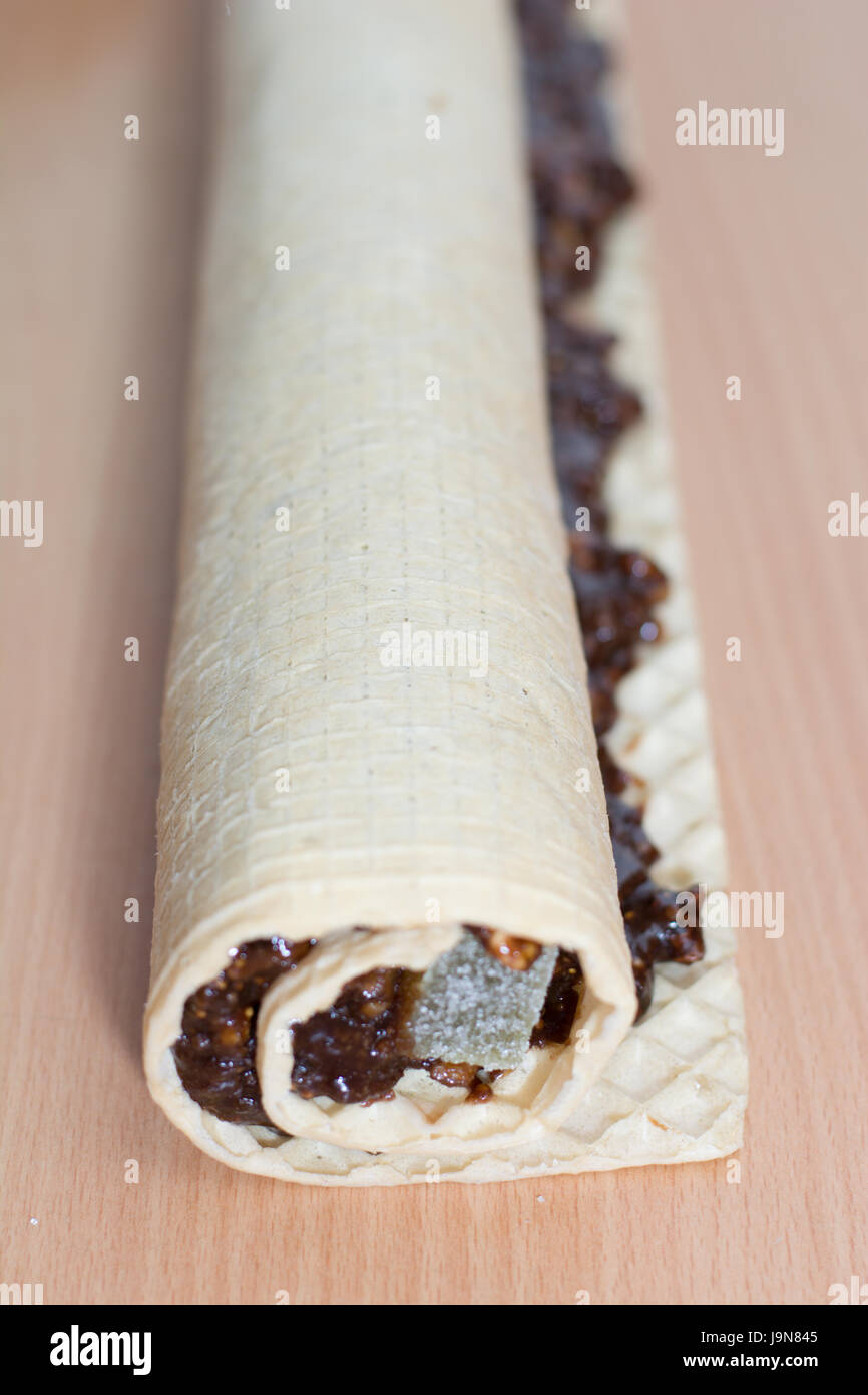 Rolling cake crust with chocolate and jelly candies. Preparing it for cutting with knife Stock Photo