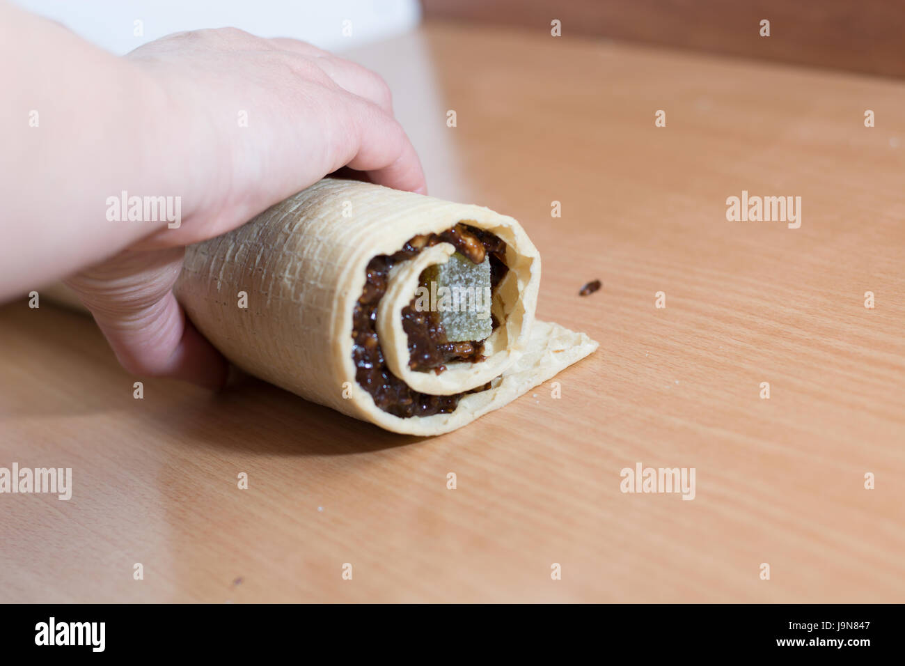 Rolling cake crust with chocolate and jelly candies. Preparing it for cutting with knife Stock Photo