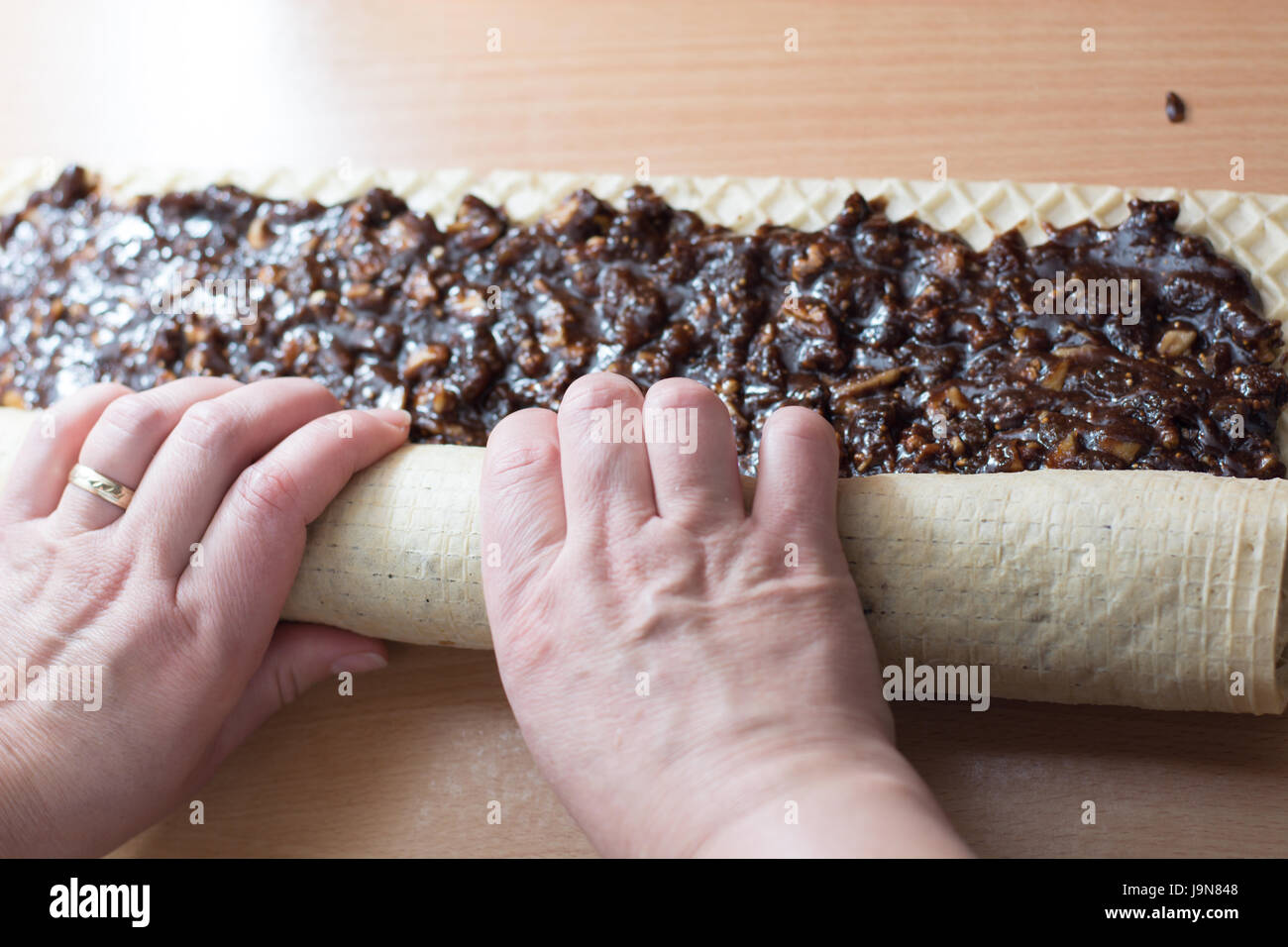 Rolling cake crust with chocolate and jelly candies. Preparing it for cutting with knife Stock Photo