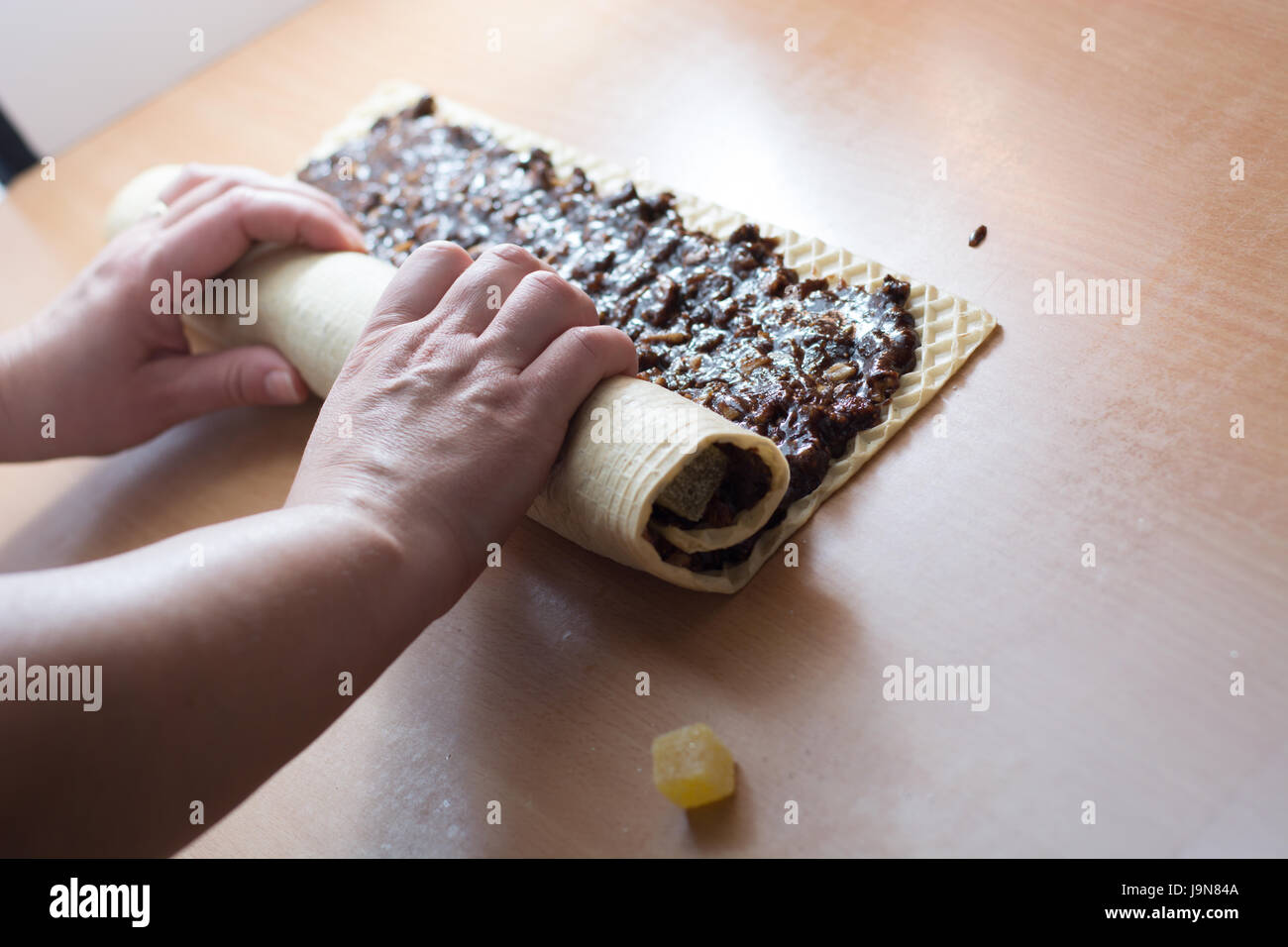 Rolling cake crust with chocolate and jelly candies. Preparing it for cutting with knife Stock Photo