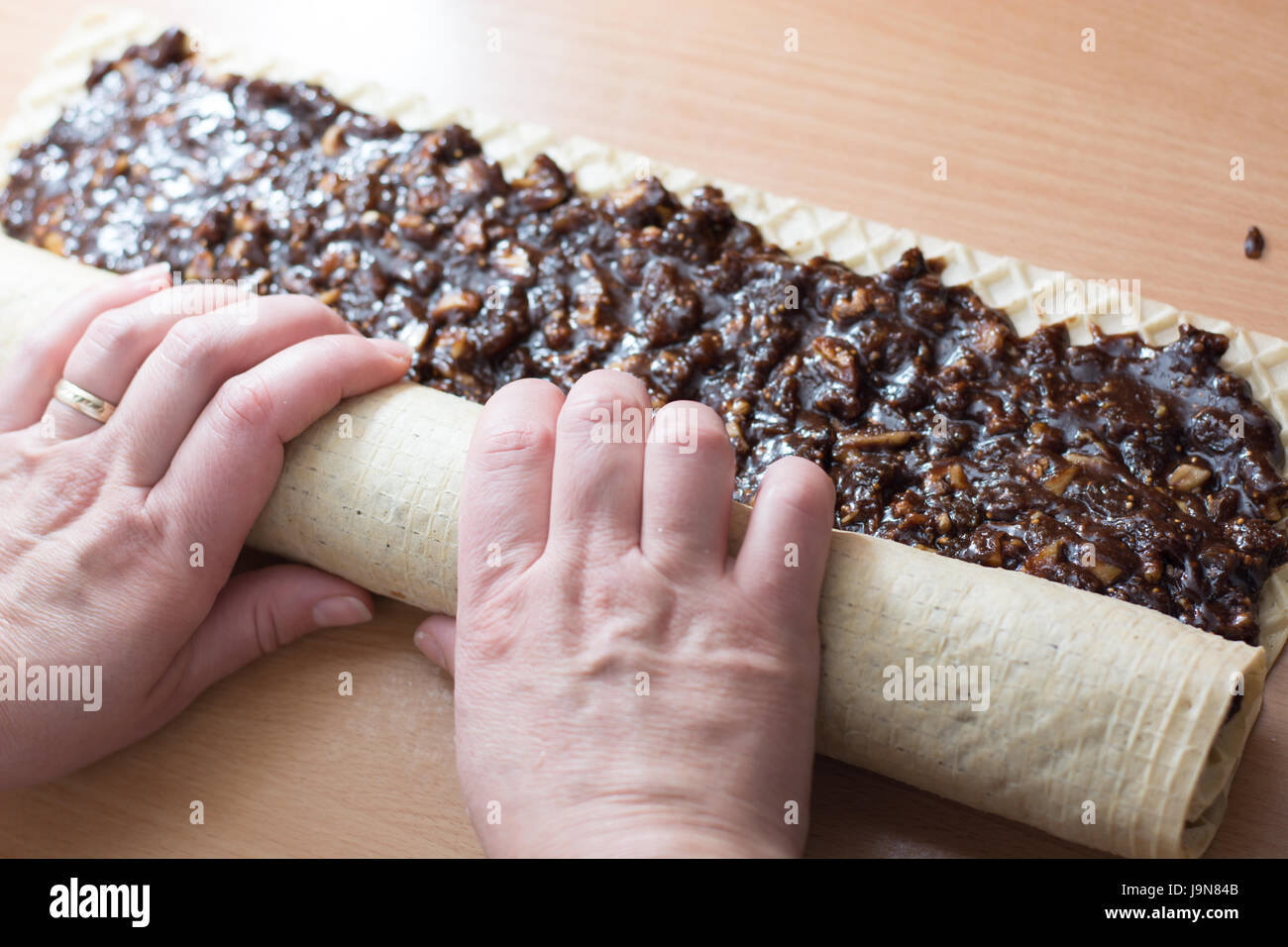 Rolling cake crust with chocolate and jelly candies. Preparing it for cutting with knife Stock Photo