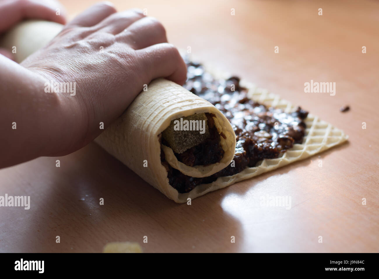 Rolling cake crust with chocolate and jelly candies. Preparing it for cutting with knife Stock Photo