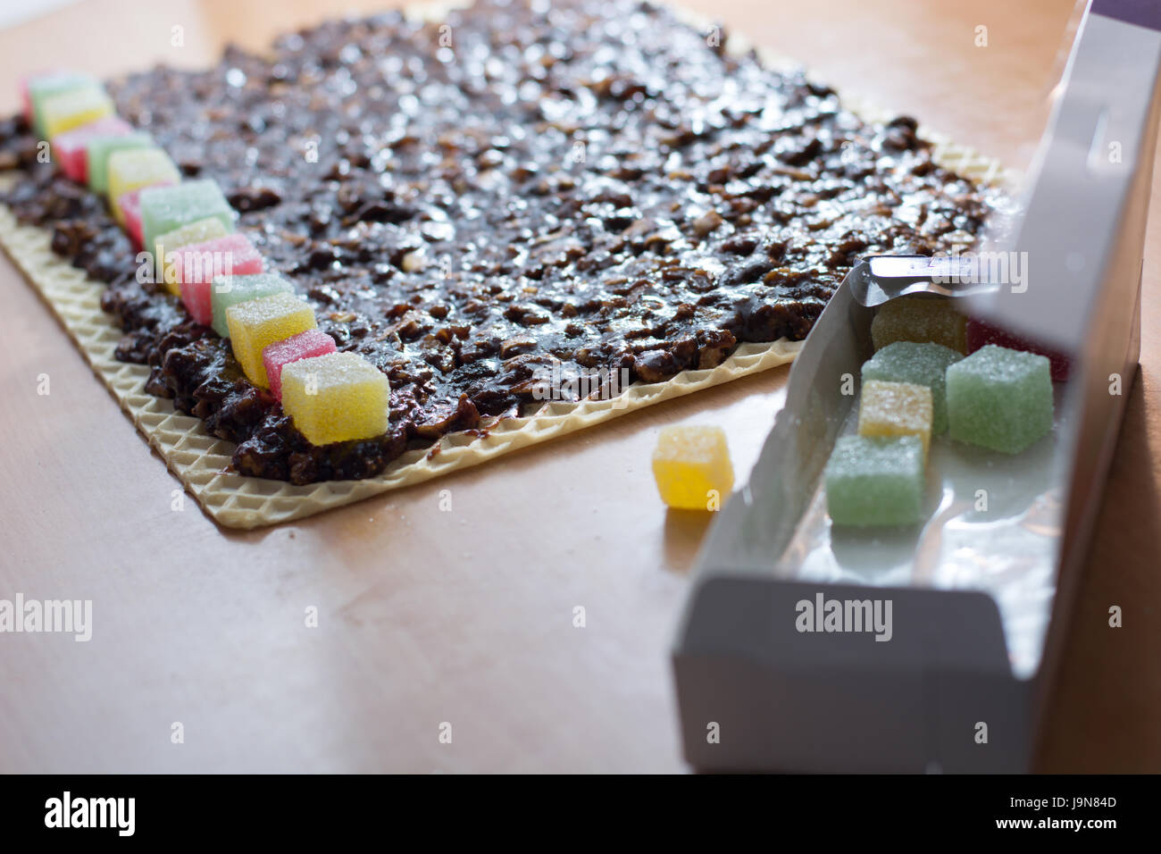 Chocolate topping with wallnuts on cake crust for rolled chocolate cake with jelly candies Stock Photo