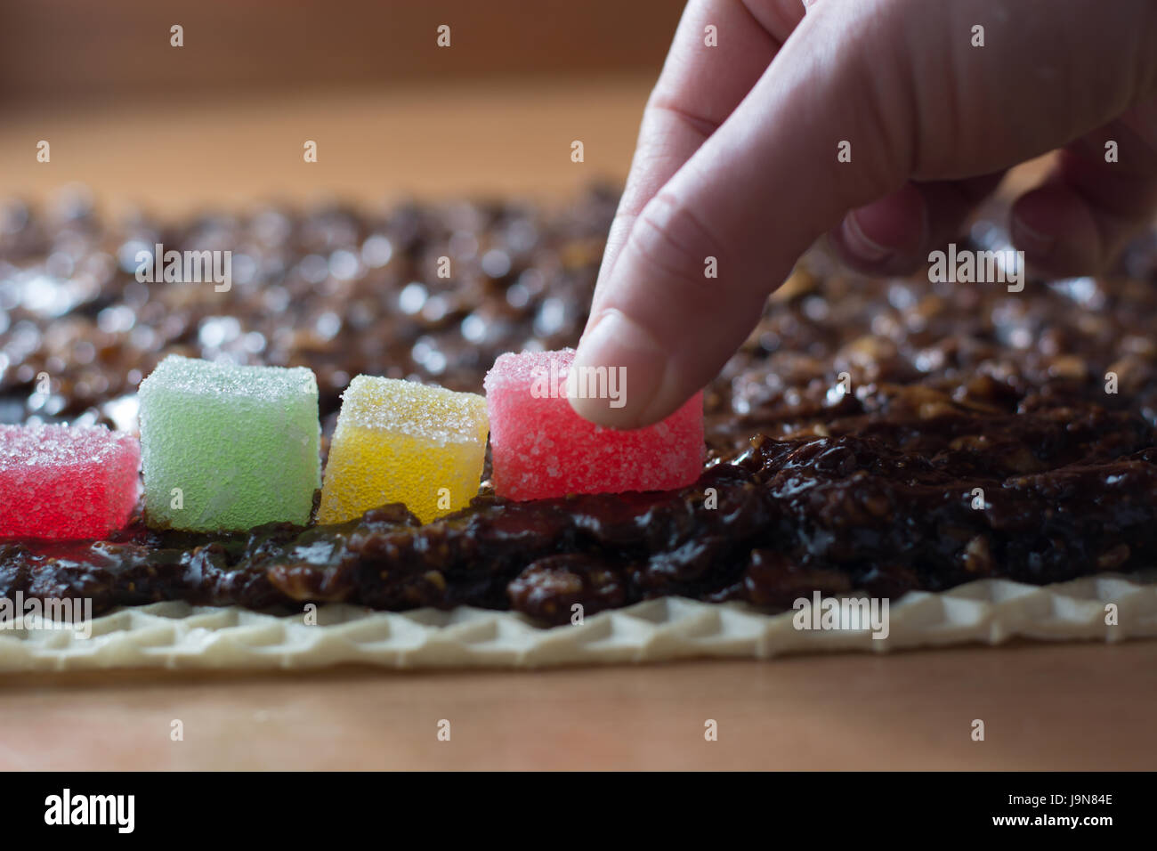 Chocolate topping with wallnuts on cake crust for rolled chocolate cake with jelly candies Stock Photo