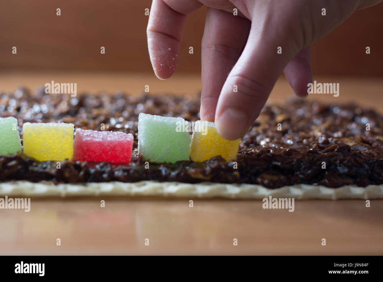 Chocolate topping with wallnuts on cake crust for rolled chocolate cake with jelly candies Stock Photo