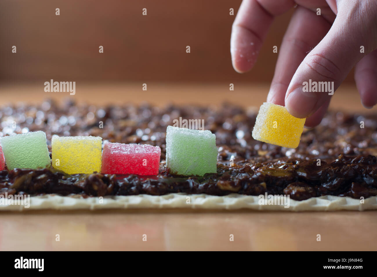 Chocolate topping with wallnuts on cake crust for rolled chocolate cake with jelly candies Stock Photo