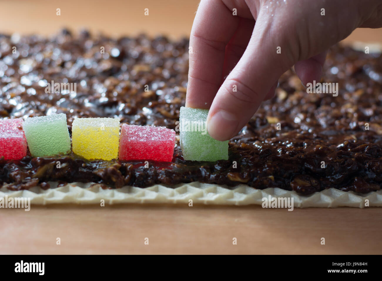 Chocolate topping with wallnuts on cake crust for rolled chocolate cake with jelly candies Stock Photo
