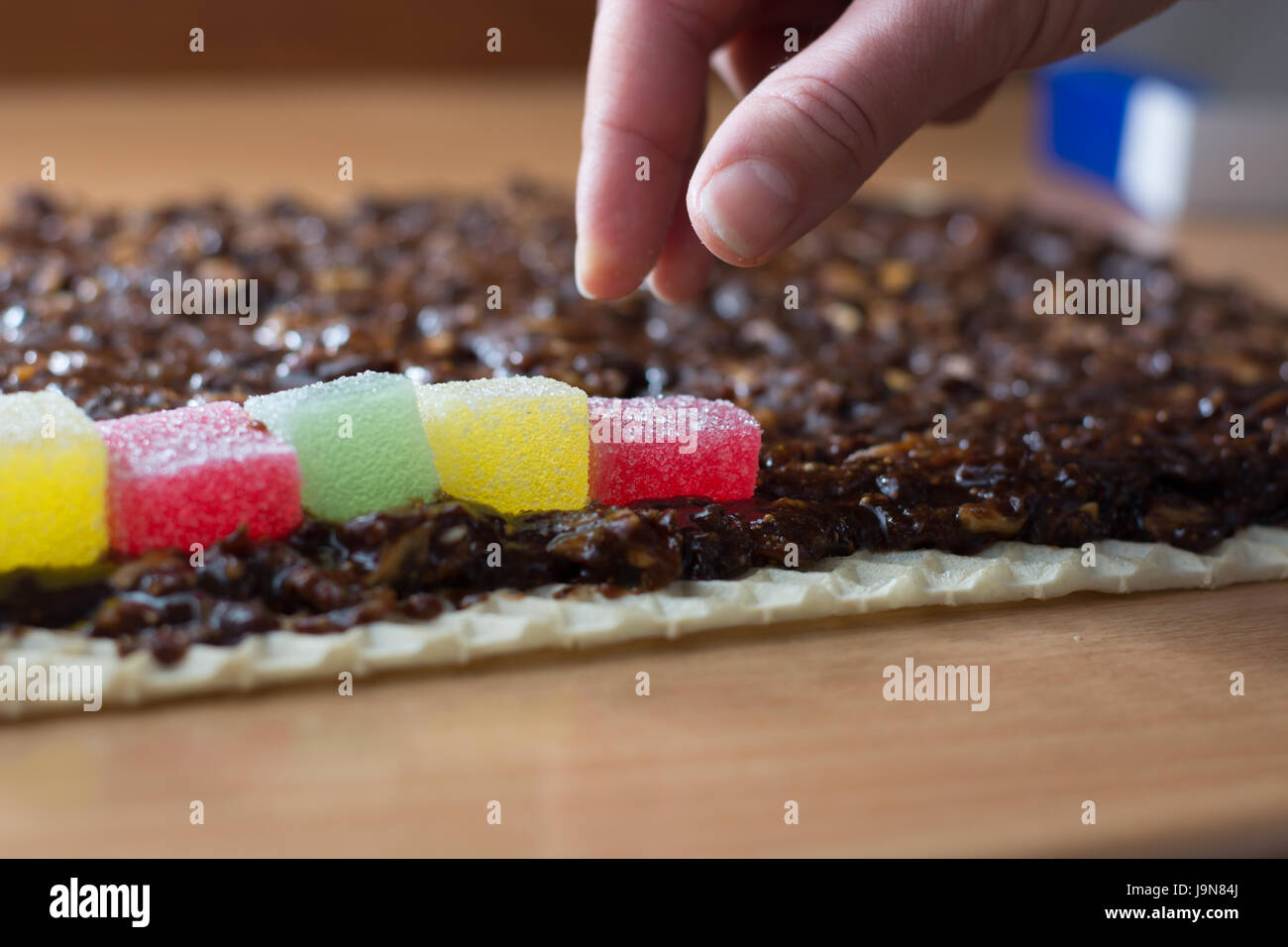 Chocolate topping with wallnuts on cake crust for rolled chocolate cake with jelly candies Stock Photo