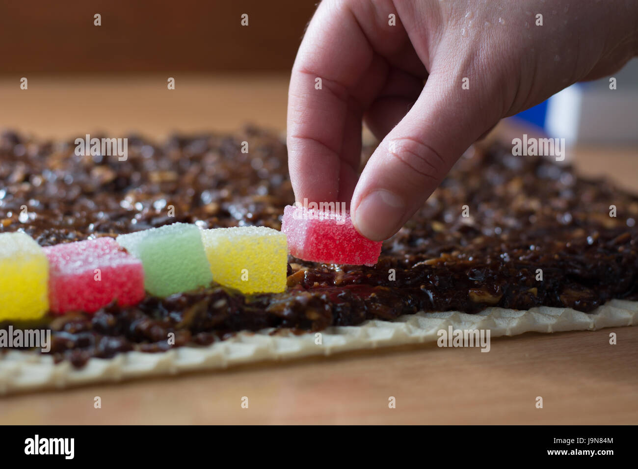 Chocolate topping with wallnuts on cake crust for rolled chocolate cake with jelly candies Stock Photo