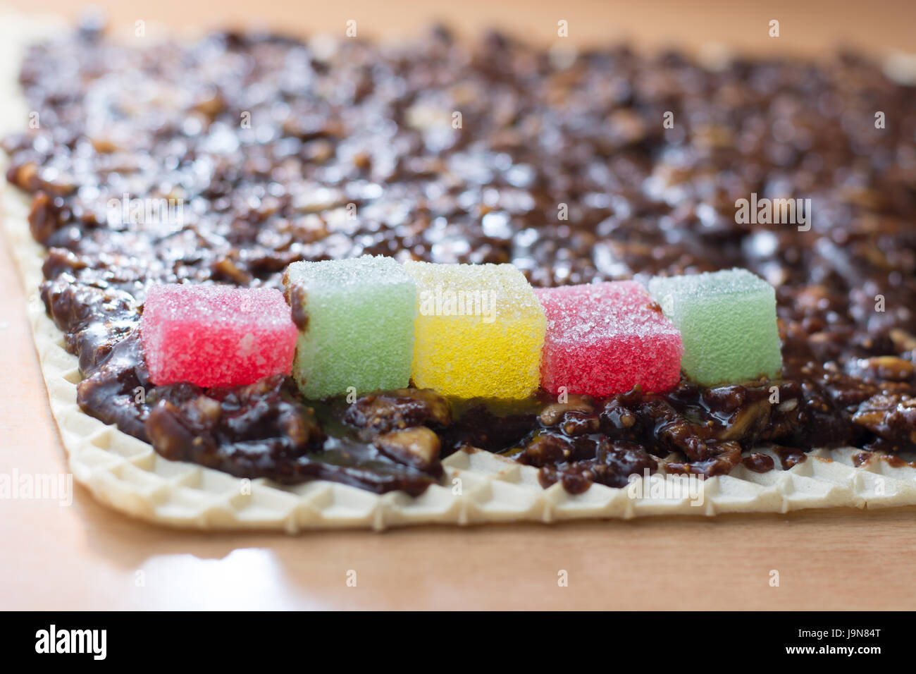 Chocolate topping with wallnuts on cake crust for rolled chocolate cake with jelly candies Stock Photo