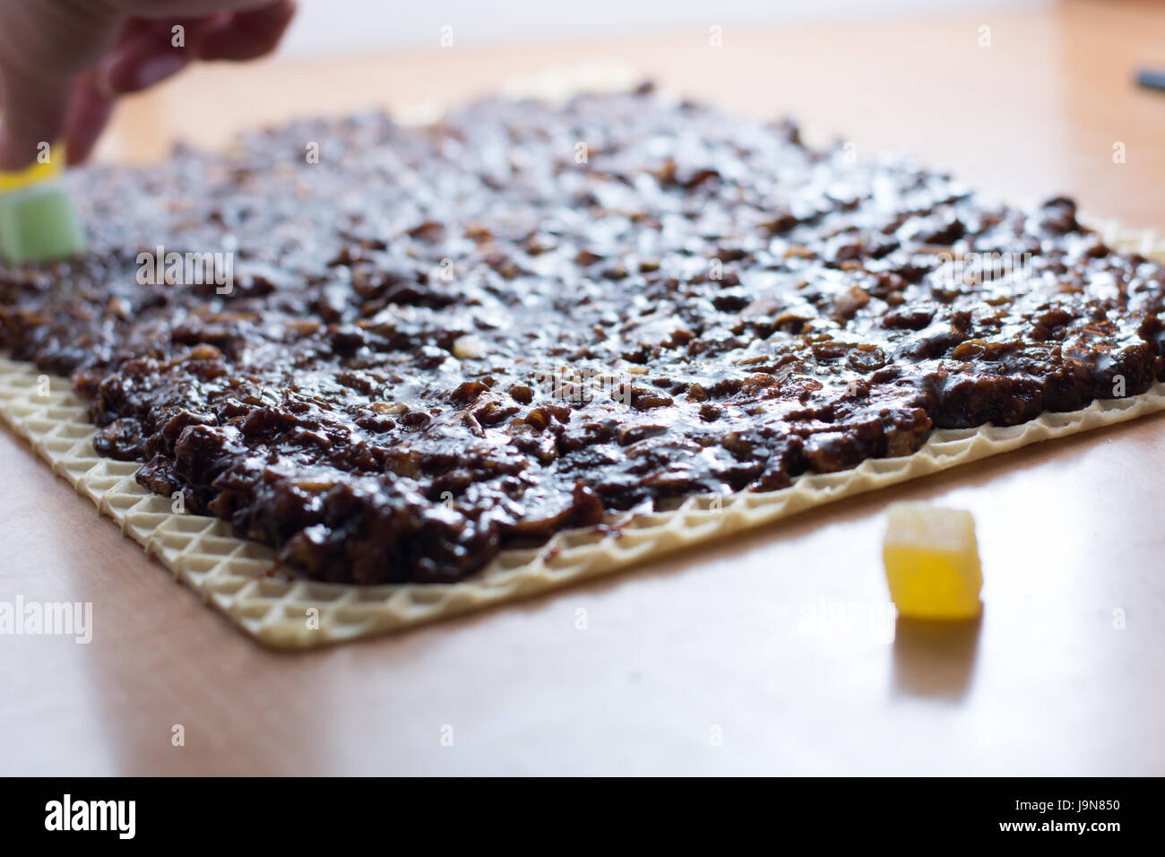 Chocolate topping with wallnuts on cake crust for rolled chocolate cake with jelly candies Stock Photo