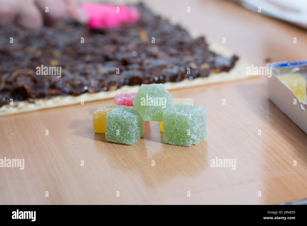 Chocolate topping with wallnuts on cake crust for rolled chocolate cake with jelly candies Stock Photo