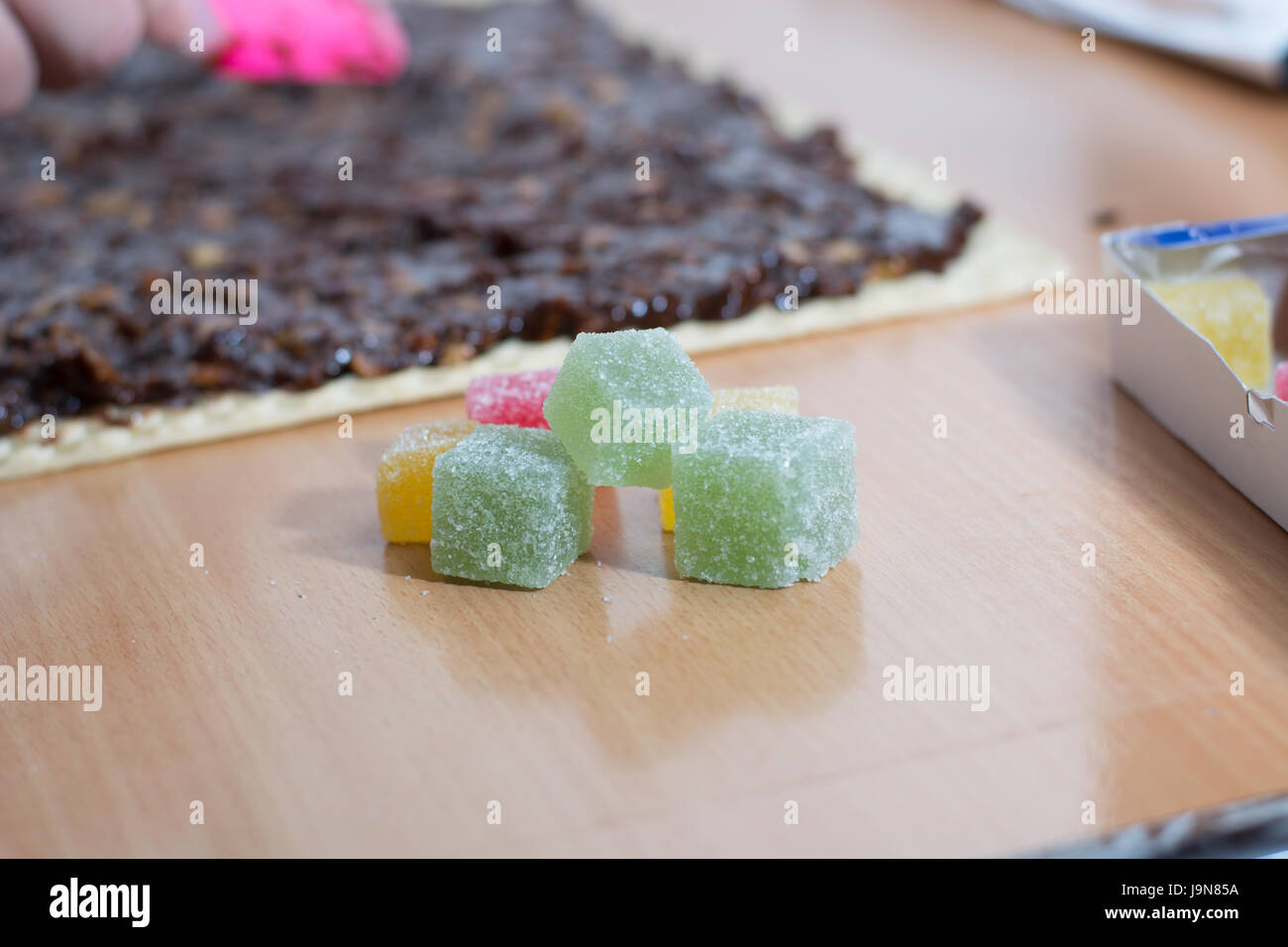 Chocolate topping with wallnuts on cake crust for rolled chocolate cake with jelly candies Stock Photo