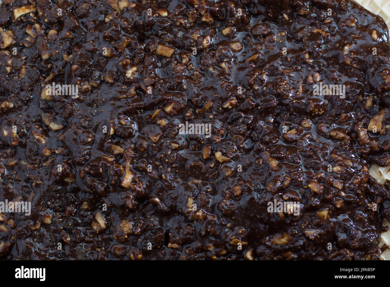 Coating chocolate topping with wallnuts on cake crust for rolled chocolate cake Stock Photo