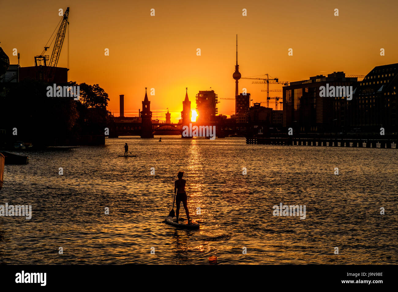 Oberbaum Bridge, Tv Tower , sunset sky and  paddle board / stand up paddler on river Spree in Berlin Stock Photo