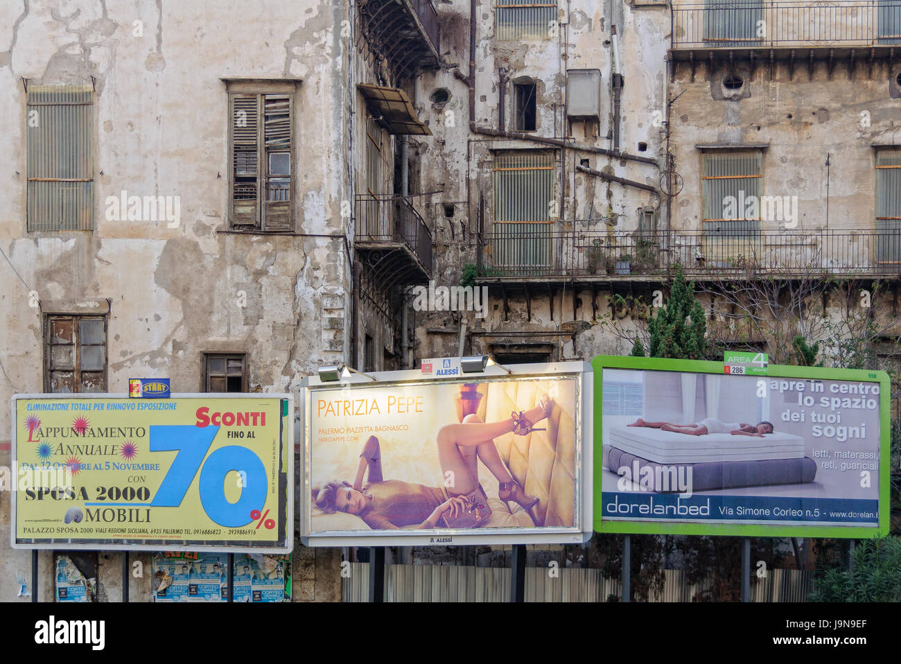 Illuminated billboards in front of a dilapidated house - Palermo, Sicily, Italy Stock Photo