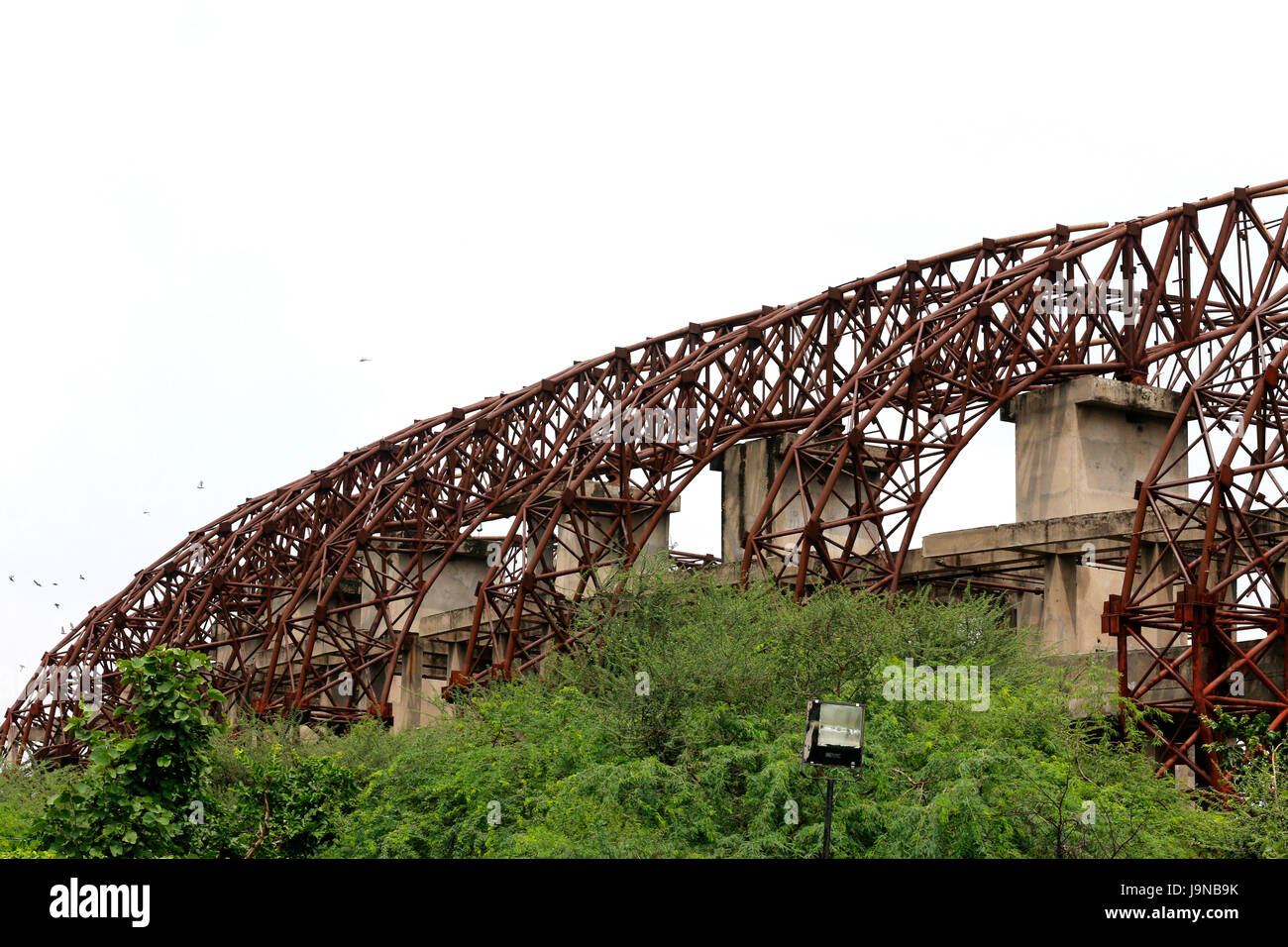 A rusted iron framework above stadium architectural form showing urbanization Stock Photo