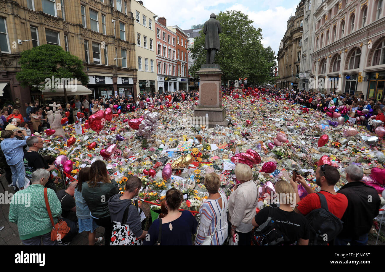 People look at flowers and tributes left in St Ann's Square in