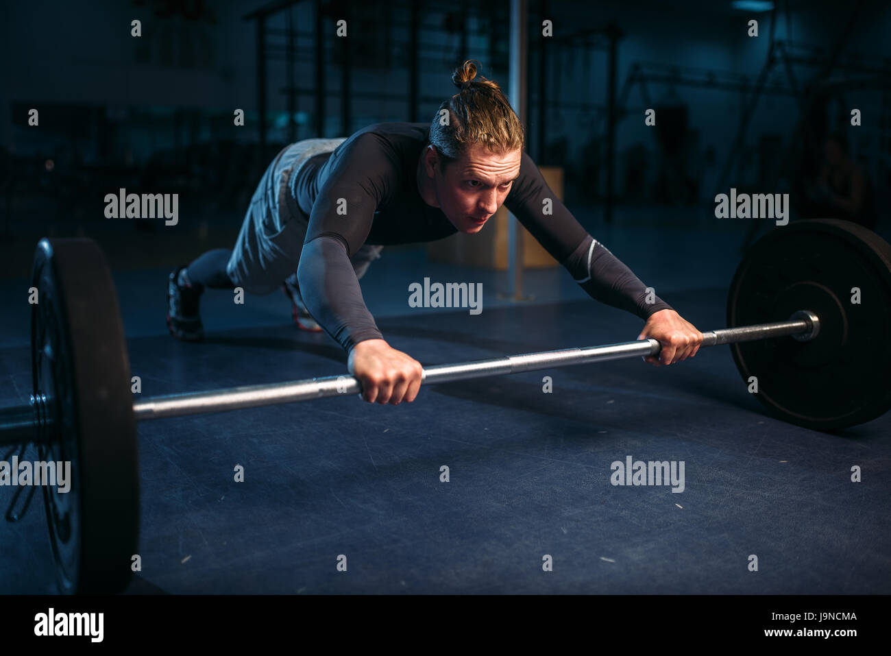 Strength athlete on training, pushups with barbell in gym. Active ...