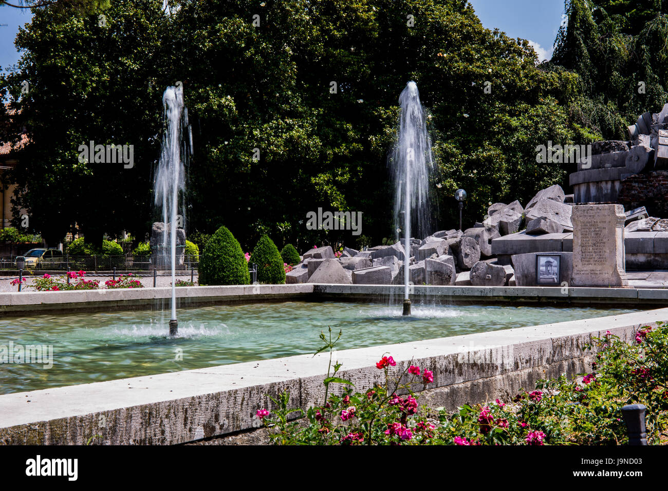 Fountain decorating the park with stone monument in the background Stock Photo