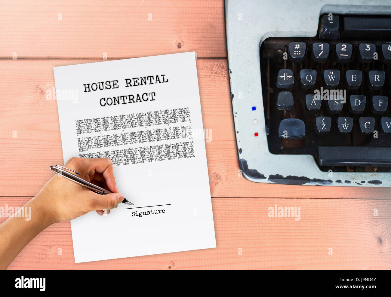 House rental agreement with hand signing on signature paper, with typewriter on wood table, vintage contract sign Stock Photo