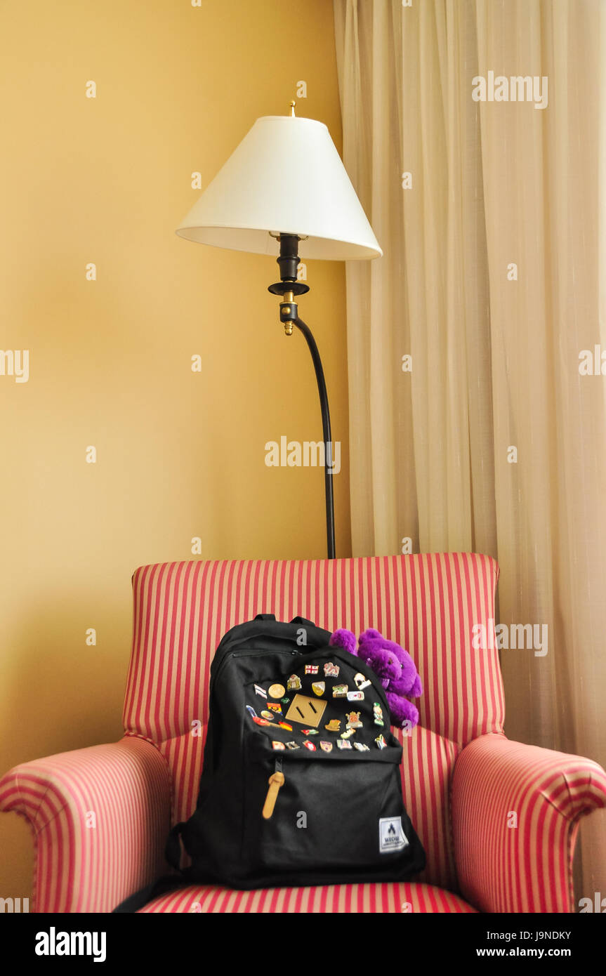 A Black Backpack With A Purble Toy Bear In It On A Red Striped