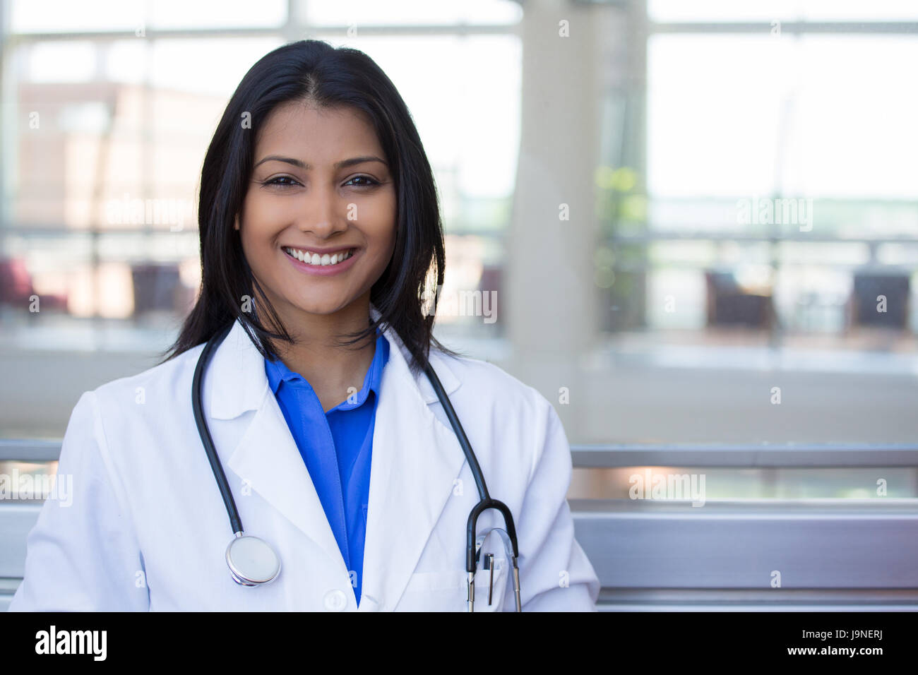 Closeup headshot portrait of friendly, cheerful, smiling confident female, healthcare professional with lab coat. isolated indoor clinic office backgr Stock Photo