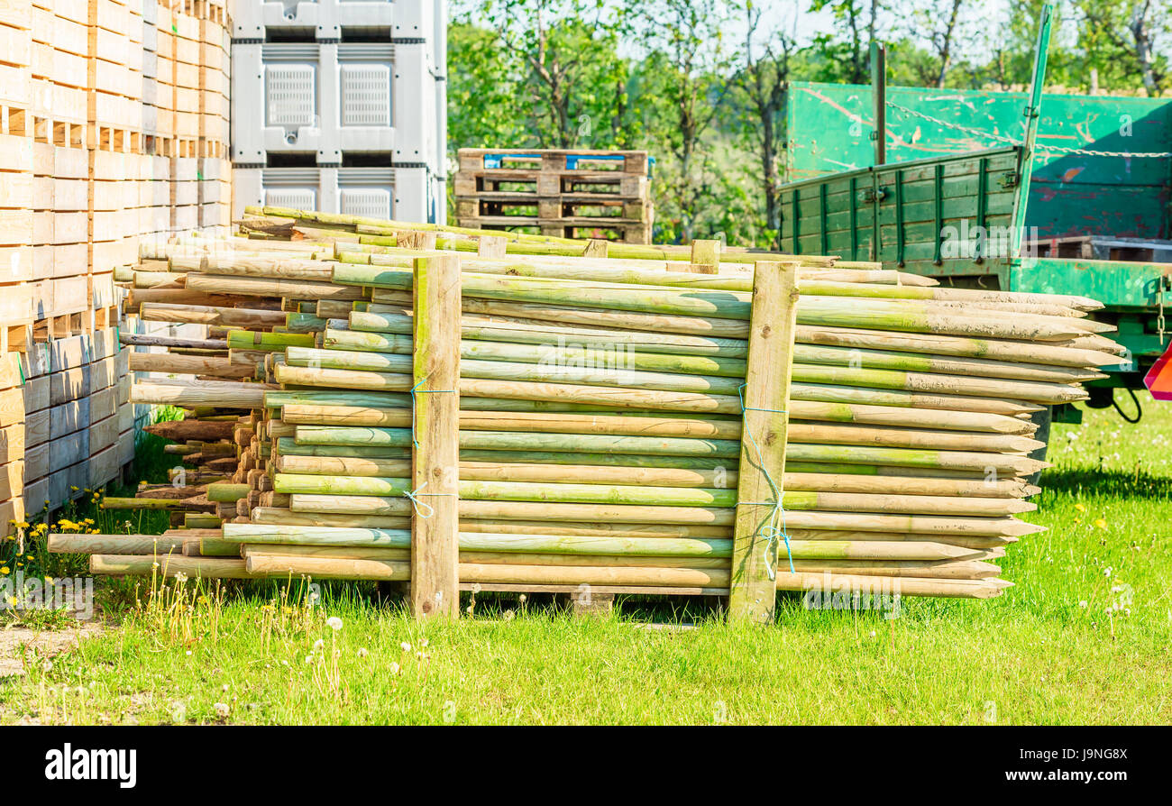 Stack of impregnated wooden fence posts on a pallet. Posts have been used so there is soil still on the sharpened ends. Stock Photo