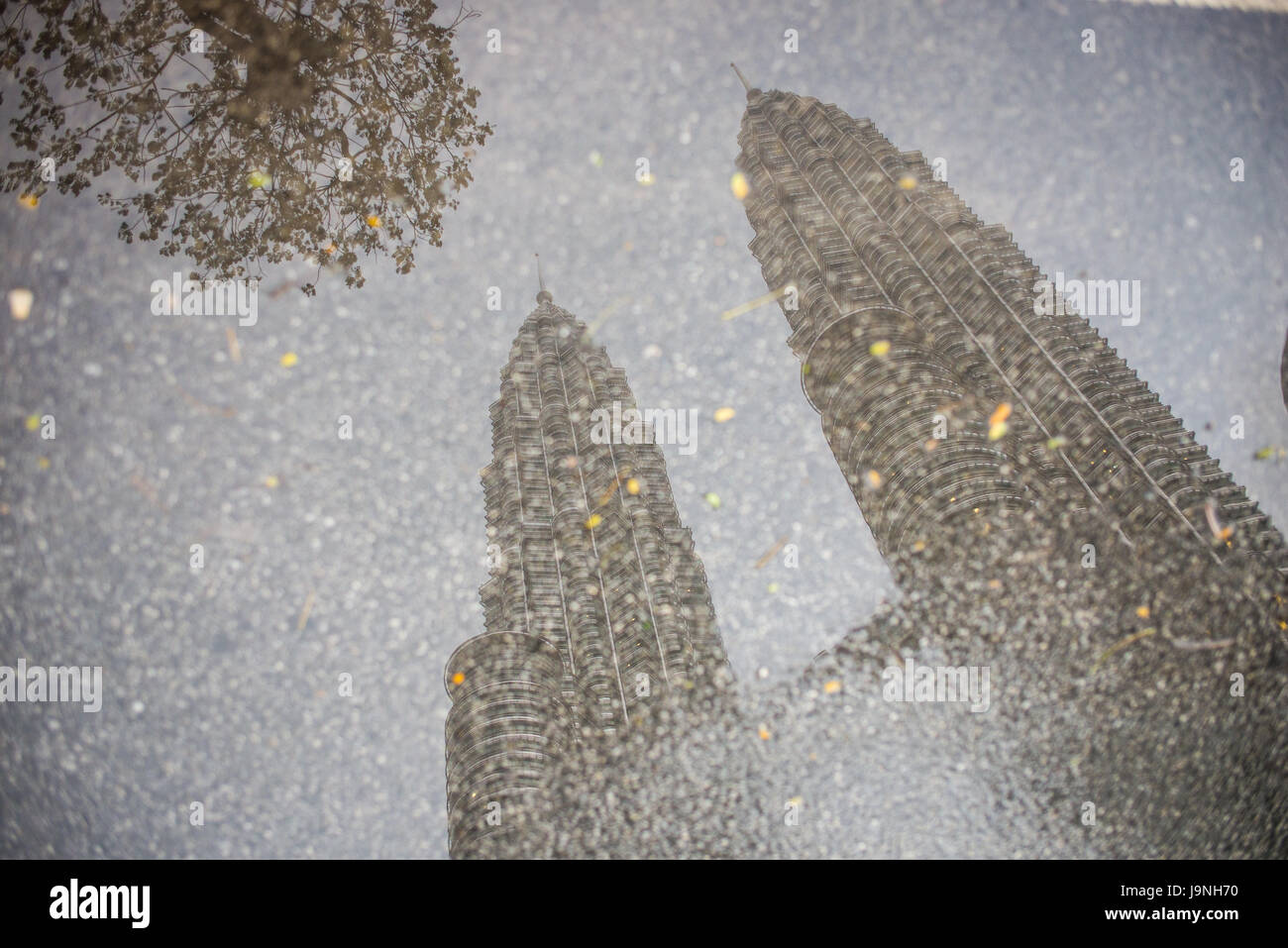 Petronas Towers seen in the reflection of a puddle in the road. Kuala Lumpur, Malaysia. Stock Photo