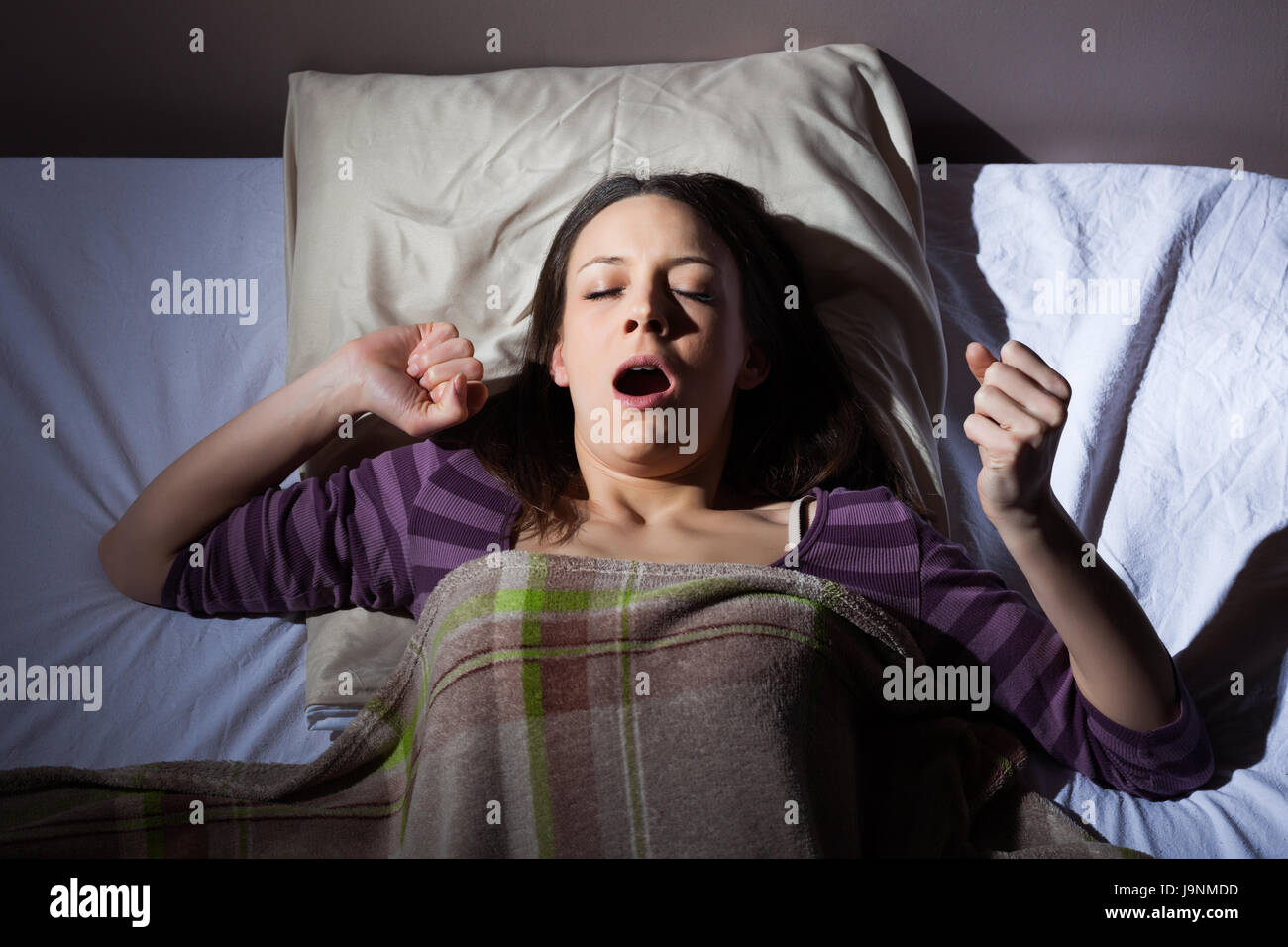 Young woman waking up early in the morning. It's time to get up for work. Stock Photo