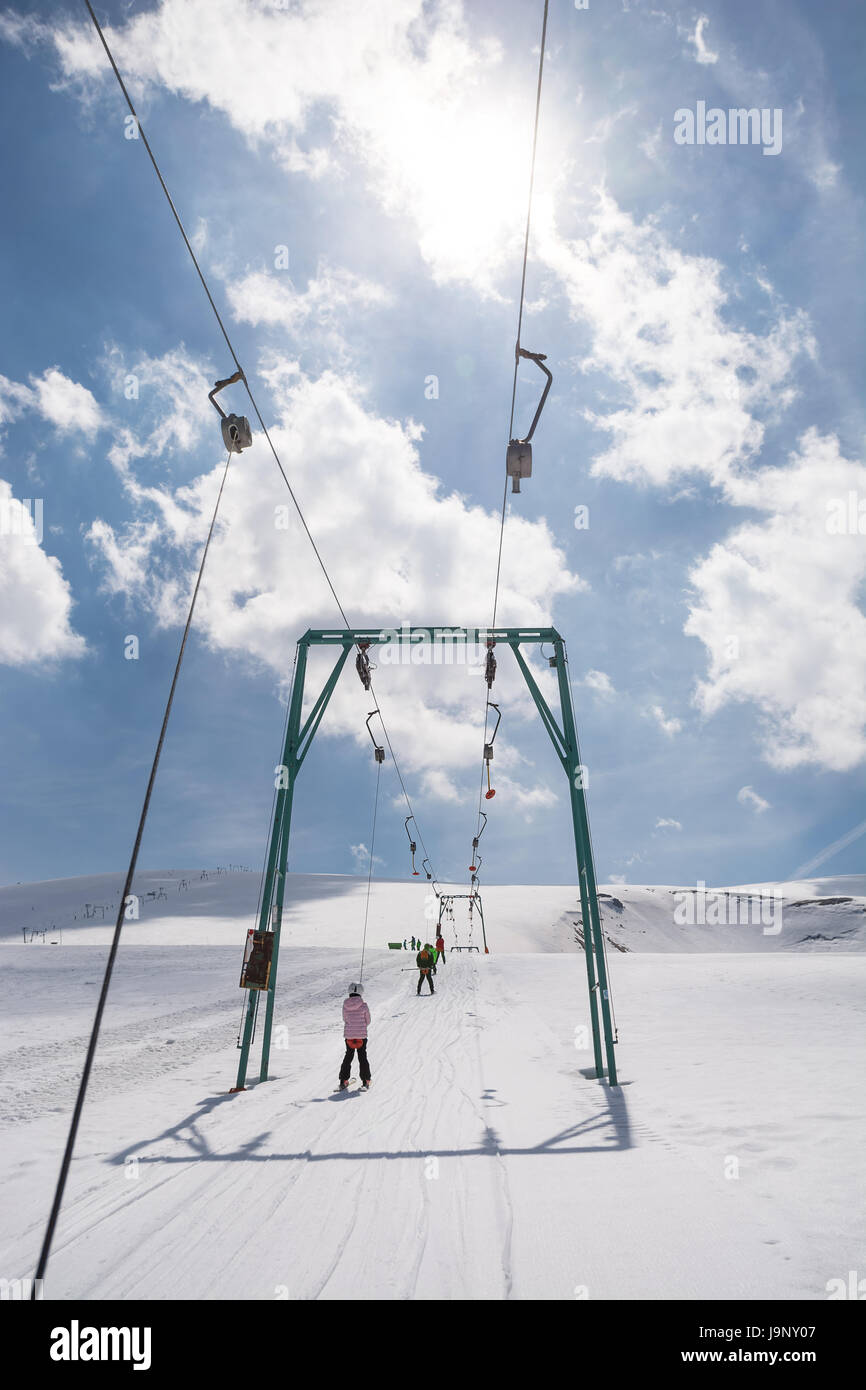 Beginner little girl with skis ascends with ski lift Stock Photo